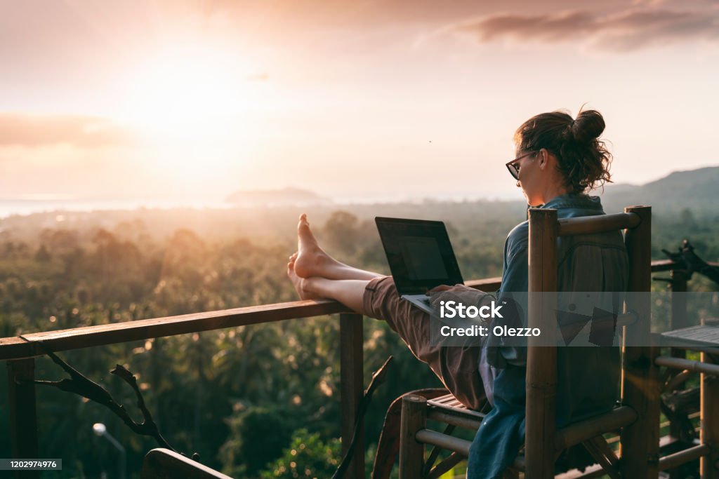 imagen6 Young business woman working at the computer in cafe on the rock. Young girl downshifter working at a laptop at sunset or sunrise on the top of the mountain to the sea, working day.